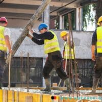 Arbeiter auf dem Bau mit Warnweste und Helm erstellen Baugerüst