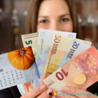 Frau hält Euro-Scheine in der Hand und einen Kalender mit dem Blatt für Oktober