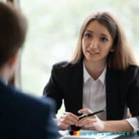 Frau sitzt am Schreibtisch und ein Mann ihr gegenüber.