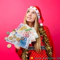 Frau in Weihnachtskostüm hält Geld in der Hand